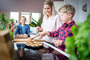 Jonge vrouw bakt poffertjes met kinderen op een inductiekookplaat